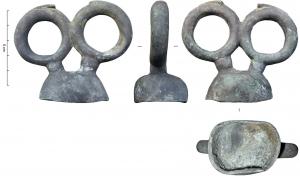 AJG-4017 - Anneau de jougbronzeDeux anneaux accolés, montés sur des tiges cylindriques, émergent d'un support hémisphérique creux ; chaque anneau semble avoir été surmonté d'une volute ou d'un appendice (forme ?), de section lenticulaire.