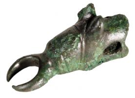 AML-3024 - AmulettebronzeTPQ : -120 - TAQ : -50Amulette en forme de tête de molosse, les oreilles pointées vers l'avant, la gueule entr'ouverte.