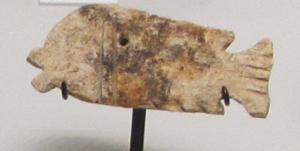 AML-4047 - Amulette en forme de poissonosAmulette plate, perforée transversalement, en forme de poisson de profil ; la tête et la queue sont détaillées.