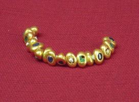 BRC-3022 - BraceletorBracelet de perles en forme de grains ovoïdes, avec incrustations d'éléments colorés (pierrerie ? émail ?) ; perforation transversale.
