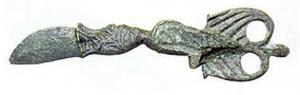 CER-9006 - CernoirbronzePetit couteau à lame courte et large, dont la transition avec le manche comporte une tête animale; le manche (en forme d'aile ?) se termine par un motif plat percé de deux ajours circulaires.