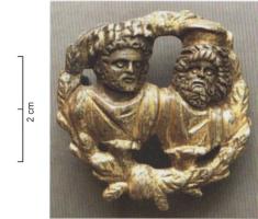 FIB-41915 - Fibule à bustes : Caracalla, Serapis, couronneargent doréBroche en forme de bustes d'un homme barbu et lauré (Caracalla) et de Sarapis, dans une couronne de feuillages ; revers creux sous les bustes, charnière articulée sur deux plaquettes coulées.