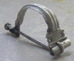 FIB-4645 - Fibule de type AucissaargentFibule d'Aucissa classique, comportant un arc systématiquement orné d'une ligne de perles médiane entre deux cannelures, une charnière martelée et retournée vers l'extérieur, un pied coudé, un bouton terminal rapporté et mouluré.