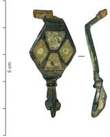 FIB-4722 - Fibule émaillée bronzeFibule à corps losangique, émaillé, avec une loge divisée en quatre (deux losanges et deux trapèzes); le pied se termine par une tête de reptile stylisée.