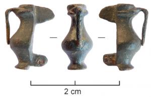 FIB-4898 - Fibule skeuomorphe : cruchebronzeFibule émaillée en forme de cruche à panse sinusoïdale; l'extrémité du manche (émaillée ou non) est ronde.