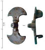 FIB-5213 - Fibule symétrique anséebronzeFibule constituée de deux éléments scutiformes symétriques, ornés d'ocelles, reliés par un arc court et massif, formant un bloc proéminent orné d'un ocelle au sommet.
