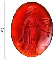 INT-4002 - Intaille : IsispierreIntaille ovale, en pierre fine (cornaline) figurant Isis debout à gauche (sur l'empreinte) : la déenne vêtue d'une longue robe couvrant jusqu'à ses pieds tient de la main droite un sistre, la gauche portant un vase d'eau lustrale.