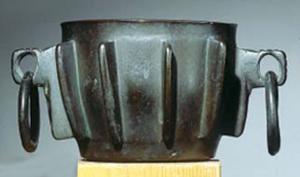 MRT-8002 - Mortier à côtesbronzeTPQ : 1500 - TAQ : 1600Mortier à large ouverture, fond plat; les côtés légèrement galbés sont ornés de côtes verticales en fort relief, qui jouent aussi le rôle de renforts; deux oreilles diamétralement opposées sont percées d'un trou rond, auquel pendent généralement des anneaux.