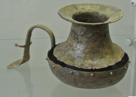 SPL-2005 - Simpulum italique à manche sinusoïdalbronzeVase à panse hémisphérique surmontée d'un col étroit, à profil concave et bord largement déversé ; une poignée fixée sur la vasque montre un profil inhabituel, en S.