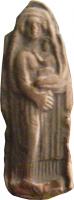 STE-4082 - Statuette : femme et enfantterre cuiteFigurine représentant une femme debout, sur une gaine mais légèrement tournée vers la gauche; vêtue d'un chiton retombant sur deux niveaux, elle tient dans ses bras un bébé assis dont la main gauche est posée sur son cou; elle est coiffé d'un voile dont les bords retombant librement encadrent tout le sommet de la figurine.