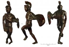 STE-4466 - Arès montant sur son charbronzeLe dieu de la guerre, sous la forme d'un jeune homme nu, portant seulement un manteau agrafé sur l'épaule droite et rejeté en arrière sur sa gauche, et coiffé d'un casque à haut cimier, est figuré en mouvement, levant le pied gauche pour monter sur son char de combat.