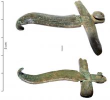 AGC-3023 - Agrafe de ceinturebronzeAgrafe étroite, à crochet, ornée de cannelures parallèles et prolongée par une patte percée et rivetée sur le cuir; une barrette transversale passée dans la patte donne la largeur de la ceinture.