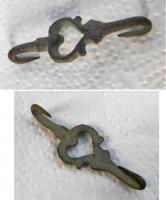 AGR-9216 - Agrafe à double crochetbronzeAgrafe composée d'un motif ajouré en forme de cœur ; au revers, deux fines pointes recoubées pour la fixation dans le vêtement.