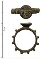 BAG-8007 - Bague IHS (bague-rosaire)bronzeTPQ : 1600 - TAQ : 1700Bague dont le jonc est marqué de 10 fortes nodosités permettant d'utiliser l'anneau comme un rosaire ; chaton circulaire surélevé, avec le monogramme IHS en lettres latines, surmonté d'une croix et une flèche vers le bas.