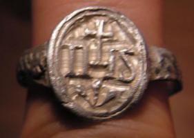 BAG-9022 - Bague IHSargentBague moulée, avec un chaton ovale perpendiculaire à l'axe de l'anneau portant la marque IHS dans une moulure, surmontant un motif floral (?).