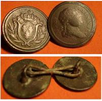 BTN-9040 - Bouton de col à thème royal : Louis XVIIIbronzeTPQ : 1814 - TAQ : 1830Bouton de col légèrement arrondi, à peine creusé d'un liseré au revers, et équipé d'une petite bélière centrale; généralement porté en paire reliée par un anneau allongé d'env. 20mm. L'un des boutons reproduit un type monétaire : buste du Roi à droite; inscription LVD.XVIII ... ; l'autre bouton présente un blason ovale aux armes de France, d'azur aux trois fleurs de lis, couronné et encadré de palmes.