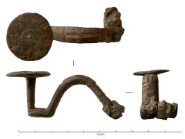 FIB-31048 - Fibule ibérique à plateau circulairebronzeFibule coulée et massive, avec un arc épais et un pied relevé à angle droit, supportant un plateau circulaire de bonne taille; la tête de l'arc est perforée pour le montage d'un ressort sur axe.
