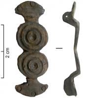FIB-41035 - Fibule symétriquebronzeFibule symetrique dont l'arc est constitué de deux cercles accolés, ornés de gorges concentriques; chaque extrémité en forme de fer de hache, possède un décor de trois cercles estampés; charnière à plaquettes.