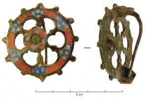 FIB-41165 - Fibule circulaire émailléebronzeFibule circulaire, comportant une bande externe simple ou avec ergots, et au centre un systême d'arcatures avec 6 pétales émaillés reliés à un élément central circulaire, émaillé et surélevé.