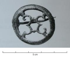 FIB-41259 - Fibule circulaire ajouréebronzeTPQ : 150 - TAQ : 260Fibule circulaire ajourée, avec deux doubles crosses adossées au centre d'un cercle lisse; articulation à ressort sur plaquettes.