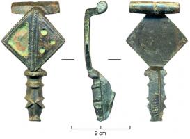 FIB-4223 - Fibule émailléebronzeTPQ : 100 - TAQ : 300Fibule à corps losangique, généralement divisé en plusieurs loges d'émail; le pied est mouluré et terminé par un bouton, une tête de reptile ou une tête animale stylisée.
