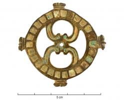 FIB-4689 - Fibule circulaire émailléebronzeFibule circulaire ajourée, composée d'une couronne accostée de quatre fleurons; au centre: deux peltes ajourées, également émaillées, enserrent entre leurs crosses un disque central surelevé, émaillé lui aussi.