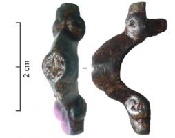 FIB-5106 - Fibule symétrique anséebronzeFibule massive, arc renflé à parois obliques,table ornée d'un motif en creux; extrémités massives à ornements latéraux  (têtes de béliers ?)