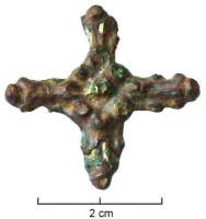 FIB-6076 - Fibule cruciformebronzeFibule en forme de croix latine, aux branches étroites ornées de bossettes encadrant un fleuron central.