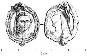 FIB-7001 - Fibule à médaillonplombFibule à médaillon ajouré, représentant un visage féminin sans doute la Vierge Marie; bordure à décor de ponctuations.