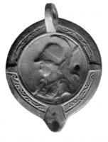 LMP-4029 - Lampeterre cuiteLampe moulée, à anse perforée, médaillon à relief moulé (tête d'Athéna casquée), bec rond encadré de deux traits obliques.