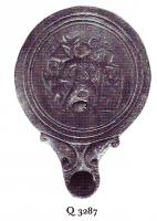 LMP-41441 - Lampe Loeschcke IV : Enée et Anchiseterre cuiteLampe ronde à bec en ogive à volutes. Médaillon décoré d'Enée portant Anchise et tenant Askanios dans leur fuite de Troie. A droite, sur une plinthe, le Palladion.