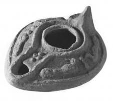 LMP-41498 - Lampe pantoufle byzantine terre cuiteLampe allongée à bec incorporé à canal, épaule décorée de traits ondulés et de cercles en relief. Anse conique.