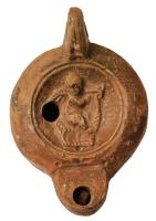 LMP-42679 - Lampe à bec rond limité par un trait : Eros portant une palme, C.OPPI.RESterre cuiteLampe moulée. Bec arrondi limité par un trait droit ponctué aux extrémités, anse verticale percée à deux sillons sur la tranche. Réservoir circulaire à profil biconvexe. Bandeau penché vers l'extérieur, disque en cuvette limitée par deux sillons concentriques. Base circulaire plate en léger relief limitée par un sillon, estampillée en creux C.OPPI.RES. Décor : Eros portant une palme.