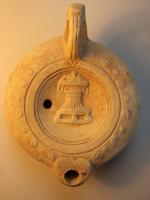 LMP-4345 - Lampe Loeschcke VIII Autel Feuille de palmeterre cuiteLampe à bec rond; disque décoré d'un autel. Argile beige, engobe orange; base plate définie par un cercle incisé; au centre feuille de palme incisée. Marque : feuille de palme incisée.