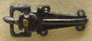 PLB-5555 - Plaque-boucle rigidebronzePlaque-boucle à plaque triangulaire, marquée par une forte côte médiane accostée de deux anneaux, prolongée sans charnière par une boucle rectangulaire ; ardillon scutiforme.