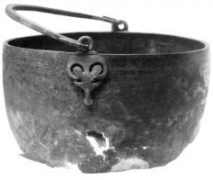SIT-4012 - Situle de type HemmoorbronzeTPQ : 150 - TAQ : 350Situle à vasque hémisphérique, lèvre verticale, dont l'attache ajourée, rapportée, comporte une pelte prolongée vers le bas par un fleuron, et surmontée d'un anneau.
