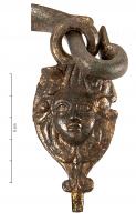 SIT-4047 - SitulebronzeSitule à panse martelée, avec une anse articulée sur deux appliques coulées fixées par brasure sous la lèvre ; elles représentent un masque enfantin au-dessus d'une languette bilobée.