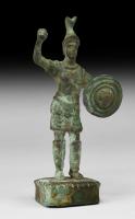 STE-4480 - Statuette : Arès - Mars cuirassé brandissant une lancebronzeLe dieu est figuré sous la forme d'un homme jeune, casqué et cuirassé. Il lève le bras droit qui brandit sans doute une lance ; le bras gauche se protège à l'aide d'un bouclier circulaire.