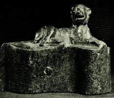 ACH-4019 - Applique de char : lionne allongéebronzeGarniture de char à profil droit mouluré en doucine renversée, sur laquelle est figurée une lionne couchée.