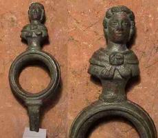 AJG-4020 - Anneau de jougbronzeAnneau entièrement coulé en bronze, constitué d'un anneau circulaire, mouluré à l'extérieur et posé sur une tige de section quadrangulaire ; il est surmonté d'un buste d'Hercule jeune (ou de Satyre ?), avec une peau de fauve nouée sur la poitrine.