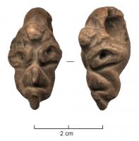 AML-4033 - Amulette : tête de GrotesquepierreTête en pierre taillée, visage déformé et grimaçant, an nez busqué; perforation transversale au sommet du crâne.