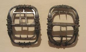 BOC-9039 - Boucle de chaussure de femmeargentBoucle rectangulaire, arquée en profil, avec un axe transversal permettant d'articuler deux doubles ardillons à griffes ; bandeau rubanné orné de décors plastiques (médaillons encadrés de barres transversales) sur tout le pourtour.