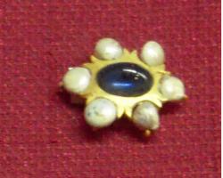 BRH-3001 - Brocheor, pierreBroche ovale formée d'une pierre sertie dans une plaque ovale, aux bords encochés pour 6 perles fines montées sur des fils perforants.