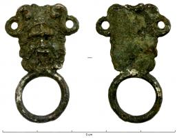DMC-9020 - Attache de demi-ceintargentAttache en forme de plaque avec deux anneaux latéraux et deux rivets de fer au sommet, en forme de tête barbue souriante (fleuve, source ?); en-dessous, anneau soudé.