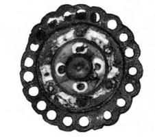 FIB-41102 - Fibule circulaire émailléebronzeFibule circulaire comportant une couronne de festons ajourés d'une succession de trous formant une dentelle périphérique; au centre, une loge circulaire surélevée creuse par en dessous, et entièrement émaillée. Le porte-ardillon est guilloché.