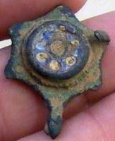 FIB-41470 - Fibule émailléebronzeFibule circulaire, mais à bord festonné (segments concaves) autour d'un disque central émaillé et surélevé; pied allongé, terminé par un bouton, masquant le porte-ardillon.