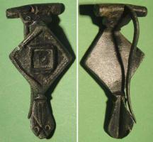 FIB-41484 - Fibule émailléebronzeFibule à charnière, dont l'arc, composé d'une plaque losangique, présente deux carrés inscrits sur pointe, et émaillés; pied en tête de reptile stylisée.