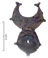 FIB-41733 - Fibule géométrique platebronzeTPQ : 40 - TAQ : 70Fibule plate, dont la charnière disposée au revers comporte deux plaquettes coulées reliées par un axe en fer. Variante en forme de pelte accolée à un un cercle, les pointes ornées de petits fleurons; décor central de cercles concentriques avec motif perlé.