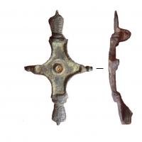 FIB-41779 - Fibule symétrique émailléebronzeFibule à arc cruciforme entièrement émaillé, prolongé dans sa longueur par deux tête de reptile; boutons moulurés sur les branches latérales.