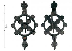 FIB-4979 - Fibule symétrique émailléebronzeFibule composée d'une couronne mince, avec 8 disques émaillés sur le pourtour, traversée par une croix composée de disques émaillés formant deux diagonales ; terminaisons symétriques en têtes de reptiles.